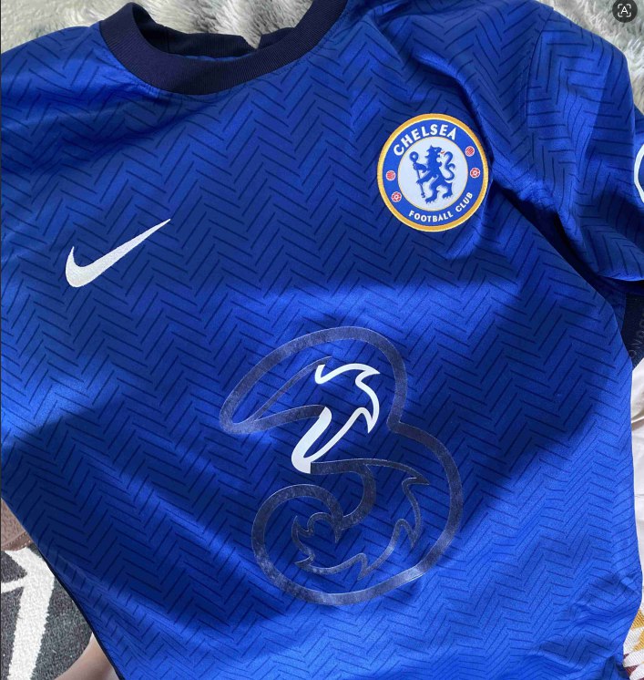 Blauw Chelsea voetbalshirt met beschadigde '3' sponsorbedrukking. Een voorbeeld van wat er gebeurt bij verkeerd wassen.