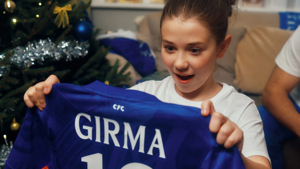 Jonge voetbalfan ontvangt een Chelsea shirt als cadeau en reageert enthousiast tijdens de feestdagen